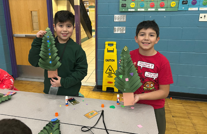 2 boys holding up their paper christmas trees and smiling